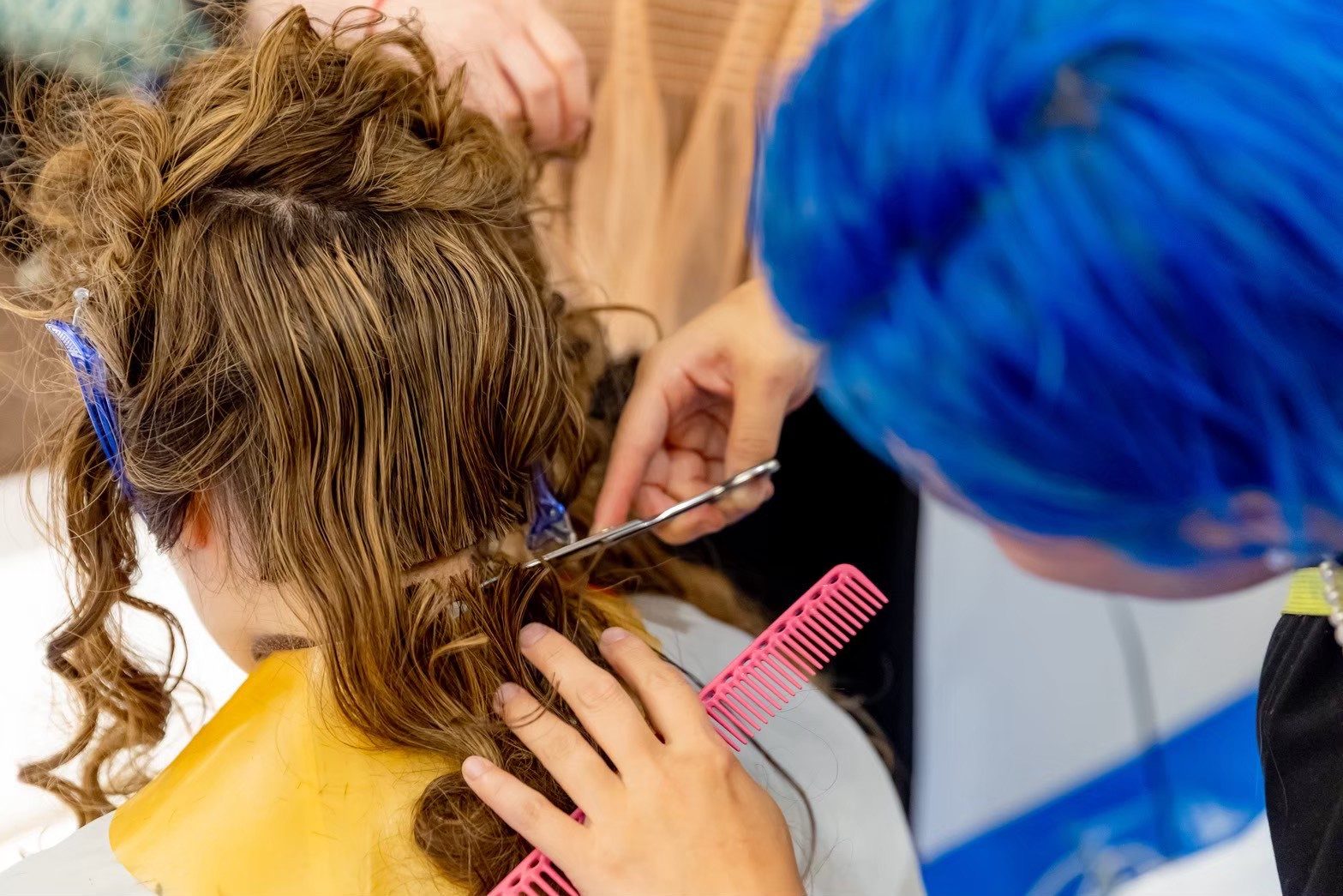 ヘアクリップで区分けした髪をハサミでカットするスタイリストの手元